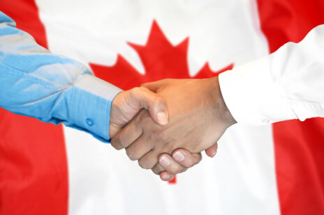 handshake on Canada flag background.