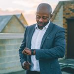 man in gray suit jacket holding black smartphone