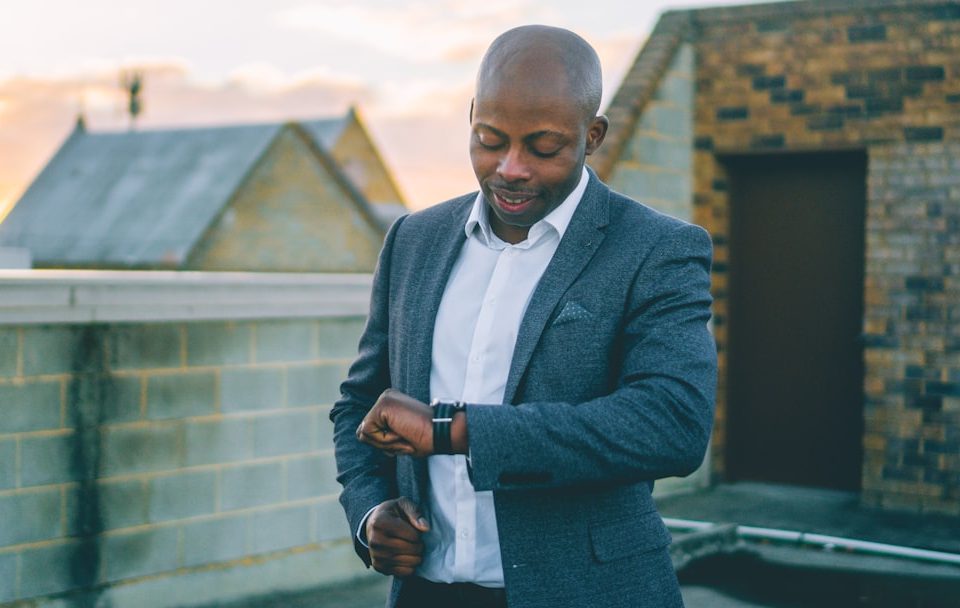 man in gray suit jacket holding black smartphone